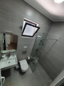 a bathroom with a shower and a toilet and a sink at Hotel Aloha in Sarandë