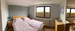 a bedroom with a bed and a desk and two windows at Gold Fehmarn in Fehmarn