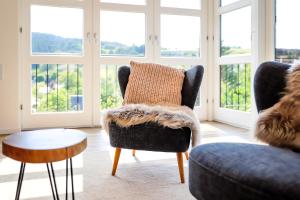 a living room with a chair and a table and windows at Sonnen Panorama - Abenteurer und Weltentdecker in Winterberg +24 photos
