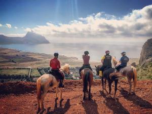 un grupo de personas montando caballos en una colina en Cala Dell'Arena, en Macari