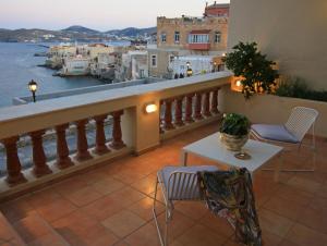 balcón con mesa, sillas y vistas al agua en Syrou Melathron en Ermoupoli