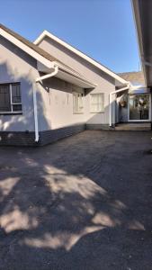 a white house with a large driveway at Utopia Guest House in Alberton