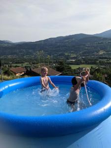 サランシュにあるChantemerle 1741, chambres d'hôtes à la montagneの青い空気入りスイミングプールで遊ぶ子供2名