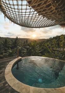 una piscina bajo una sombrilla en un complejo en Kalma Bamboo Eco Lodge en Kuta Lombok