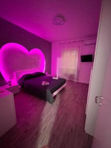 a bedroom with a heart shaped bed and purple lighting at Appartamento con SPA I Due cuori in Taranto