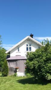 a white house with a porch and an umbrella at Småbruket stall solheim in Rødby
