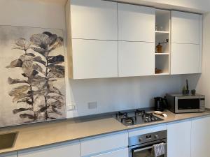 a kitchen with white cabinets and a microwave at Pogri House Unità in Trieste