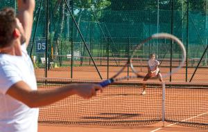 dos mujeres jugando al tenis en una pista de tenis en S2 Conchiglia, en Isola Albarella