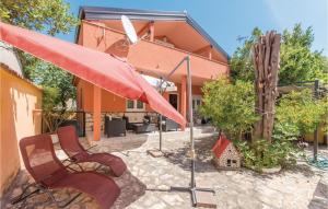 eine Terrasse mit 2 Stühlen und einem roten Regenschirm in der Unterkunft Cozy Home In Vrsi With Wifi in Vrsi