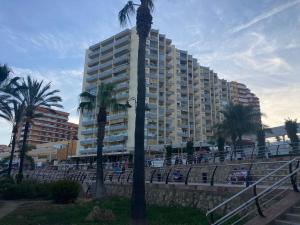 wysoki budynek z palmami przed nim w obiekcie Estudio Benalmádena Costa w mieście Benalmádena