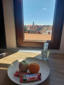 talerz z jabłkiem i dwa pomarańcze na stole w obiekcie Picky Apartment w mieście Arad