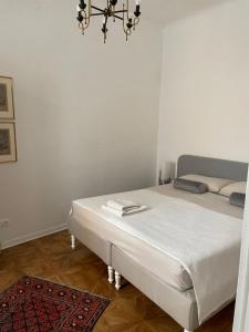 a white bedroom with a bed and a chandelier at Pogri House Unità in Trieste