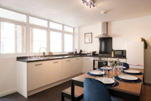 a kitchen with a table and chairs and a kitchen with white cabinets at Glevum Lodge - 2 Bedroom Town Centre Apartment in Cirencester