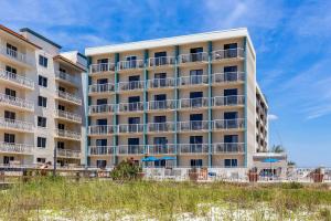 um edifício de apartamentos na praia com areia e relva em Sleep Inn on the Beach em Orange Beach