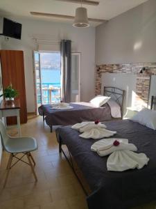 una camera d'albergo con tre letti e asciugamani di Meltemi a Posidhonía