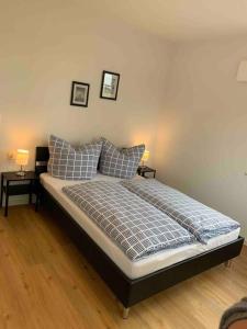 a bedroom with a bed with pillows and two tables at Ferienhaus Meerzeit in Krummhörn