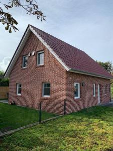 a red brick house with a fence in front of it at Ferienhaus Meerzeit in Krummhörn
