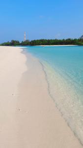 Mystic Maldives Mathiveri Retreat في ماثيفيري: شاطئ رملي فيه ماء وأشجار في الخلف