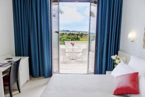 a hotel room with a bed and a table and a balcony at Tenuta La Baronessa Resort in Tuglie