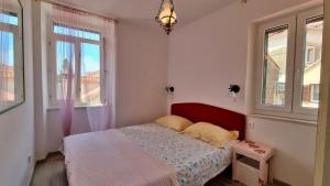 a small bedroom with a bed and two windows at Apartment Adagio in Omiš