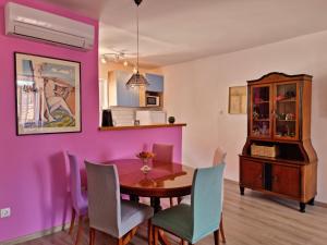 a dining room with purple walls and a wooden table and chairs at Apartment Adagio in Omiš