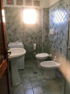 een badkamer met 2 wastafels, een toilet en een raam bij Residence Cala Chiesa in La Maddalena