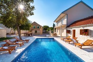 a swimming pool with chairs and a house at kuća za odmor ZARA in Stankovci
