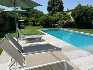 um par de cadeiras e um guarda-sol ao lado de uma piscina em La Gomerie Chambres d'Hotes em Saint-Émilion