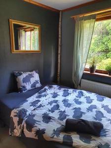 a bedroom with a bed with a blue comforter and a window at Schnieders1German forest B&B in Harmånger