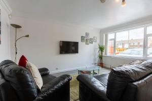 a living room with a leather couch and a tv at Hullidays East Modern Detached 3 Bed House in Hull