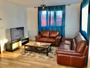een woonkamer met lederen meubels en een televisie bij Duplex agréable et spacieux 3 chb dont 1 communicante in Vendeville