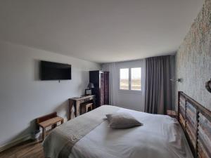 a bedroom with a large bed and a television at Hôtel Vauban in Le Palais
