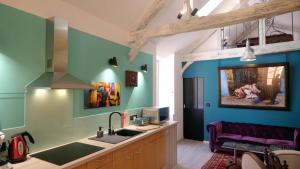 a kitchen with blue walls and a sink and a couch at LE LOFT DE LA SALAMANDRE SARLAT in Sarlat-la-Canéda