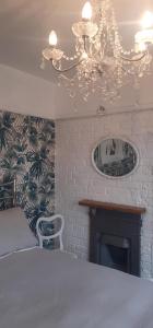 a bedroom with a bed and a chandelier and a fireplace at Coastguard Cottage Newquay in Newquay