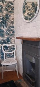 a white chair sitting next to a fireplace with a mirror at Coastguard Cottage Newquay in Newquay
