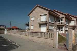 uma casa com uma cerca em frente em Desconectaengalicia La Lanzada, a pie de playa em A Lanzada