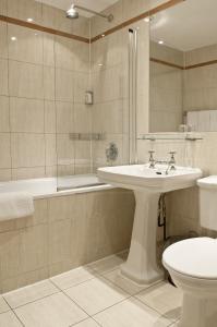 a bathroom with a sink and a tub and a toilet at Rushmore Hotel in London