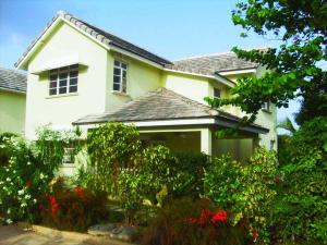 a white house with trees and flowers in front of it at Surfer's Paradise Retreat - Gated Community Townhouse for Surfers & Families in Christ Church