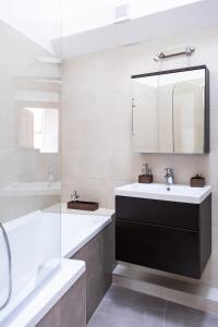 ein Badezimmer mit einem Waschbecken, einer Badewanne und einem Spiegel in der Unterkunft Sziklai Apartman in Veszprém
