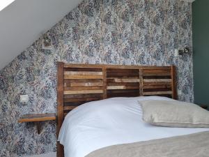 a bed with a wooden headboard and floral wallpaper at Hôtel Vauban in Le Palais