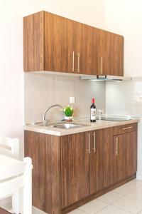 - une cuisine avec des placards en bois et une bouteille de vin dans l'établissement DIMITRIS STUDIO, à Polychrono