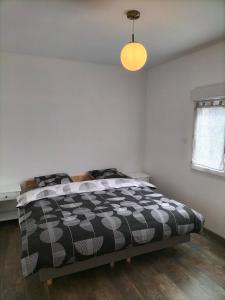 1 dormitorio con 1 cama con edredón blanco y negro en Maison plain pied 4 personnes parking gratuit, en Vendeville