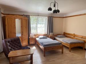 a room with two beds and a couch and a chair at Jaundzērvītes viesu nams in Loža