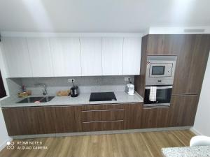 Una cocina con gabinetes blancos, un fregadero y un microondas. en Villa Lupita, en Sanxenxo