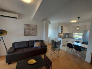 ein Wohnzimmer mit einem Sofa und einem Tisch sowie eine Küche in der Unterkunft Apartments Fugosic in Punat