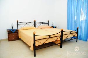 een slaapkamer met een groot bed met gele lakens en blauwe gordijnen bij Karyatides Apartments in Kariá