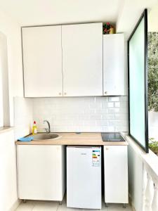 a kitchen with white cabinets and a sink at Hortus Apartments in Sveti Stefan