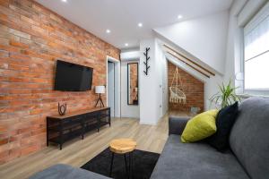 - un salon avec un canapé et un mur en briques dans l'établissement Apartments & Room Forest, à Slunj