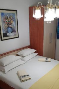 uma cama com duas almofadas brancas e uma fotografia na parede em Villa Ana em Pag