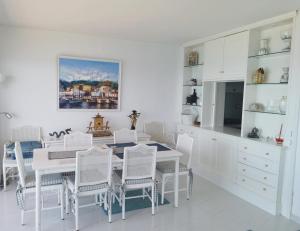 a white dining room with a white table and chairs at Spacious seafront apartment in Platja d'Aro